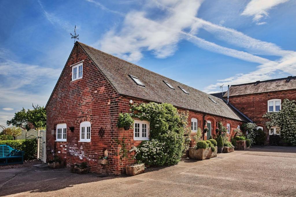 a red brick building with white windows and plants at Hollington Barns in Ashbourne