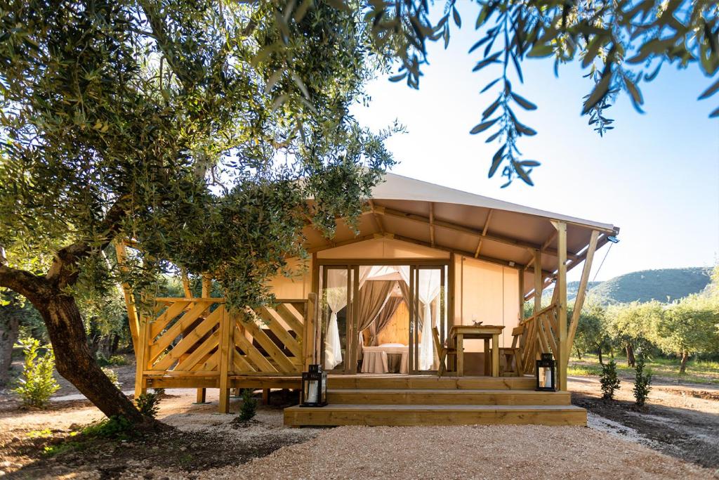 a tiny house with a porch and a tree at Le Lenze Don Mimì Glamping in Mattinata