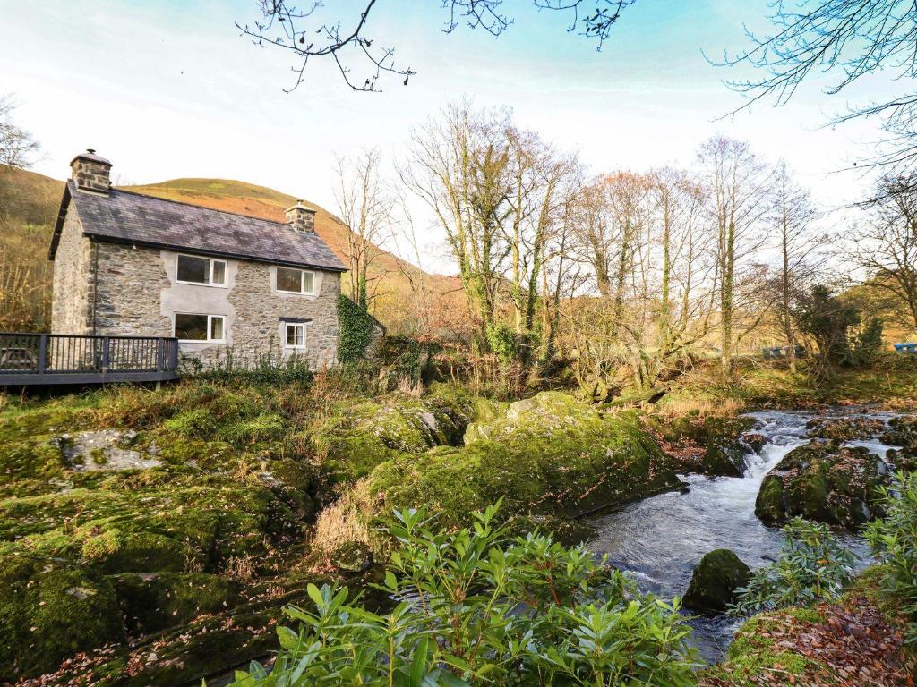 an old house on a hill next to a stream at Pen y Bont in Machynlleth