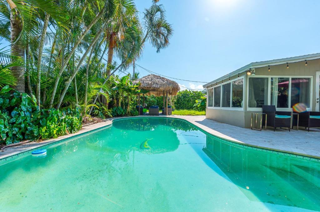 a swimming pool in front of a house at Private Oasis on Quiet Street! Pool + Tiki Hut! in Pompano Beach