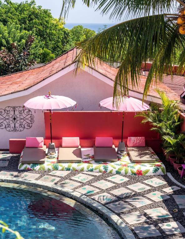 een zwembad met stoelen en parasols naast een zwembad bij PinkCoco Uluwatu - Constant Surprises & for Cool Adults Only in Uluwatu