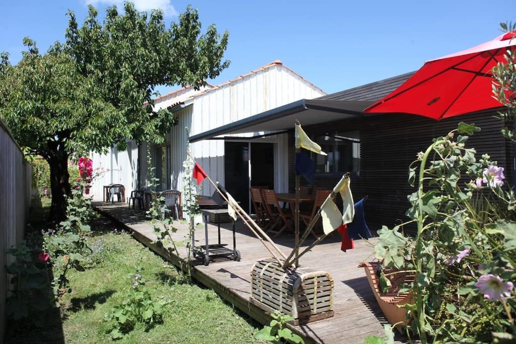 une maison dotée d'une terrasse en bois avec un parasol rouge dans l'établissement maison la rochelle quatres chambres bord de mer, à La Rochelle