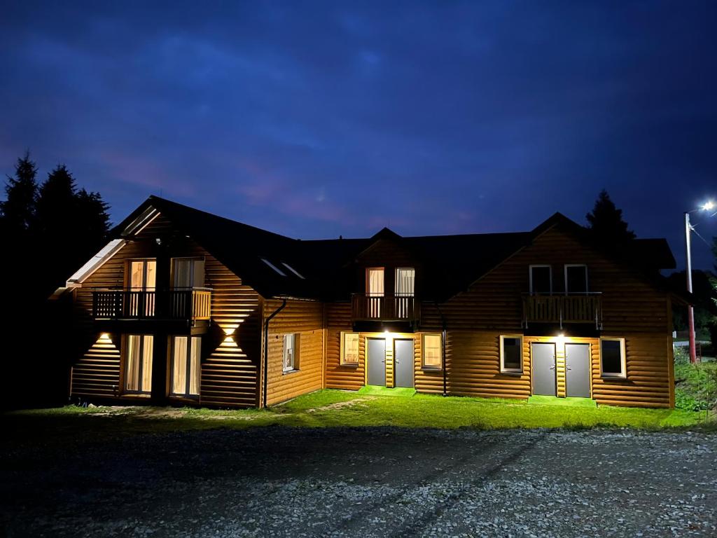 a wooden house at night with its lights on at Apartamenty u Jakubika in Krynica Zdrój