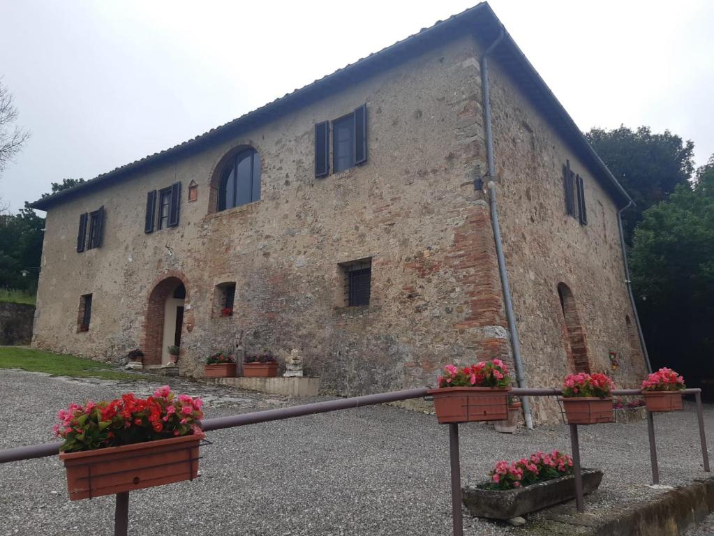 an old stone building with flowers in front of it at Tipico casolare toscano Tenuta della Selva in Grotti