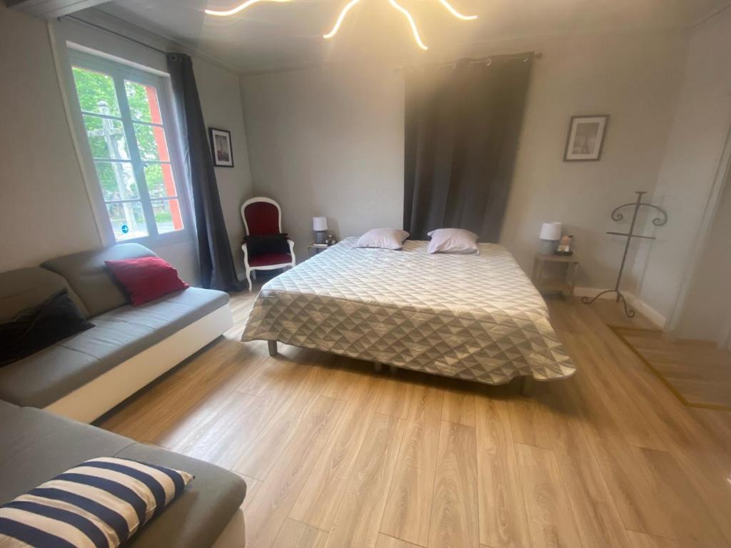 een slaapkamer met een bed en een bank in een kamer bij Hôtel restaurant l'escale chez mimi in Bioule