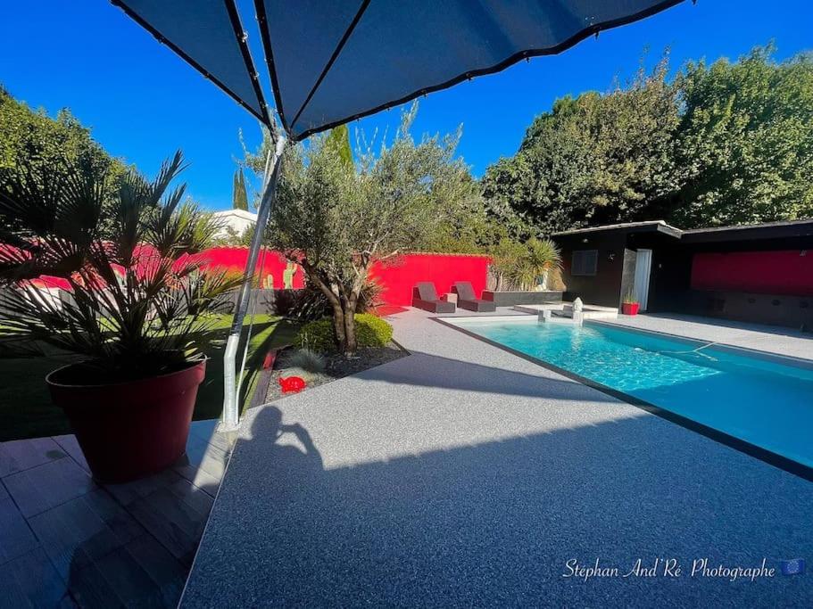 een zwembad met een parasol in de tuin bij Grande villa Calme & Piscine Rochelle / île de Ré in Dompierre-sur-Mer