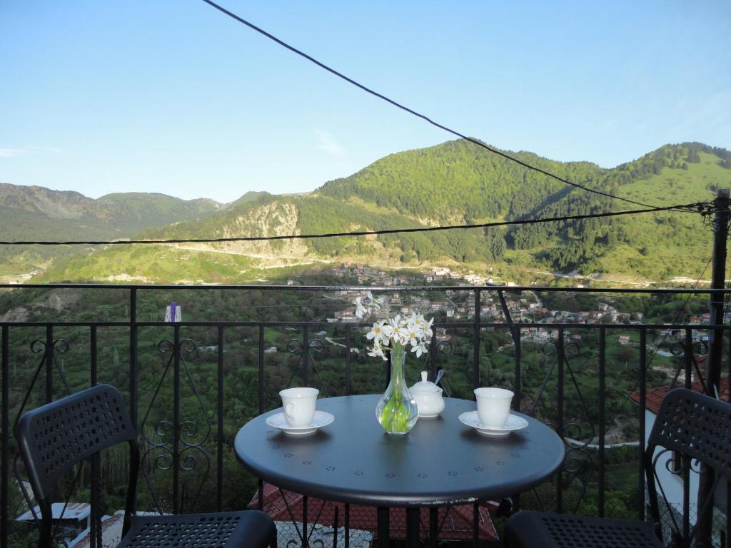 einen Tisch mit einer Blumenvase auf dem Balkon in der Unterkunft Baou House 1 in Metsovo