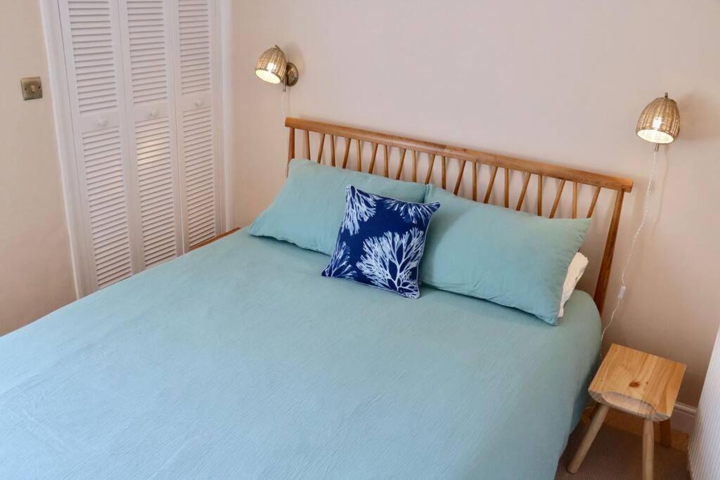 a bedroom with a blue bed with two blue pillows at Bumblebee cottage Exmouth in Exmouth