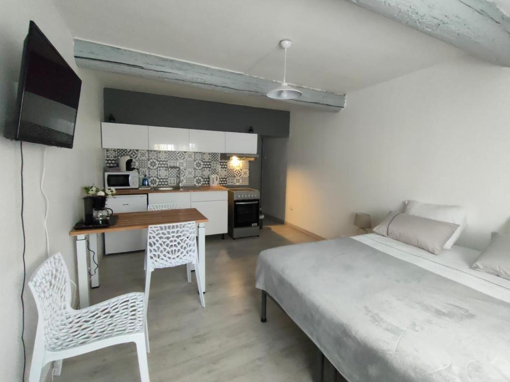 1 dormitorio con cama, escritorio y cocina en Studio Entier en Saint-Laurent-dʼAigouze