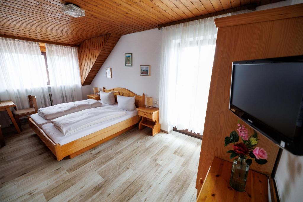 a bedroom with a bed and a flat screen tv at Drexl Gasthof Shiro in Schondorf am Ammersee