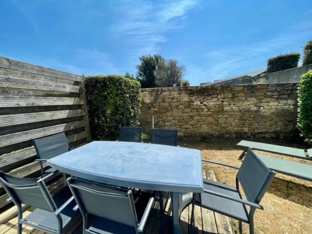 une table et des chaises bleues sur une terrasse dans l'établissement Appartement 2 pièces à Quiberon - 43m², proche plage et commerces, rez-de-jardin avec terrasse et parking - FR-1-478-245, à Quiberon