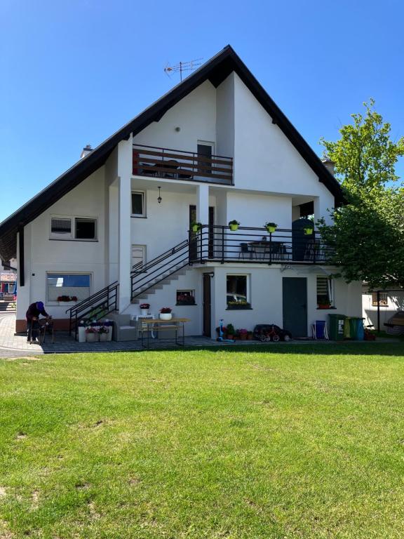 a large white house with a grass yard at AGAT Pokoje Gościnne Apartamenty in Pobierowo
