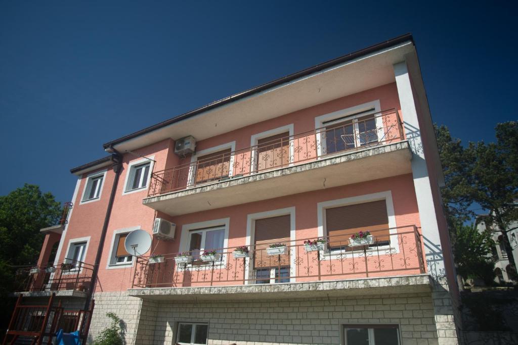 ein großes rosafarbenes Gebäude mit Balkon oben in der Unterkunft Apartment Galjanić in Buzdohanj