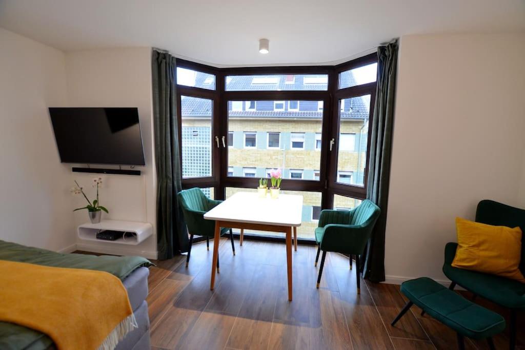 een woonkamer met een tafel en stoelen en een raam bij Studio 7 City Lage mit Garage nähe Köln Bonn in Siegburg