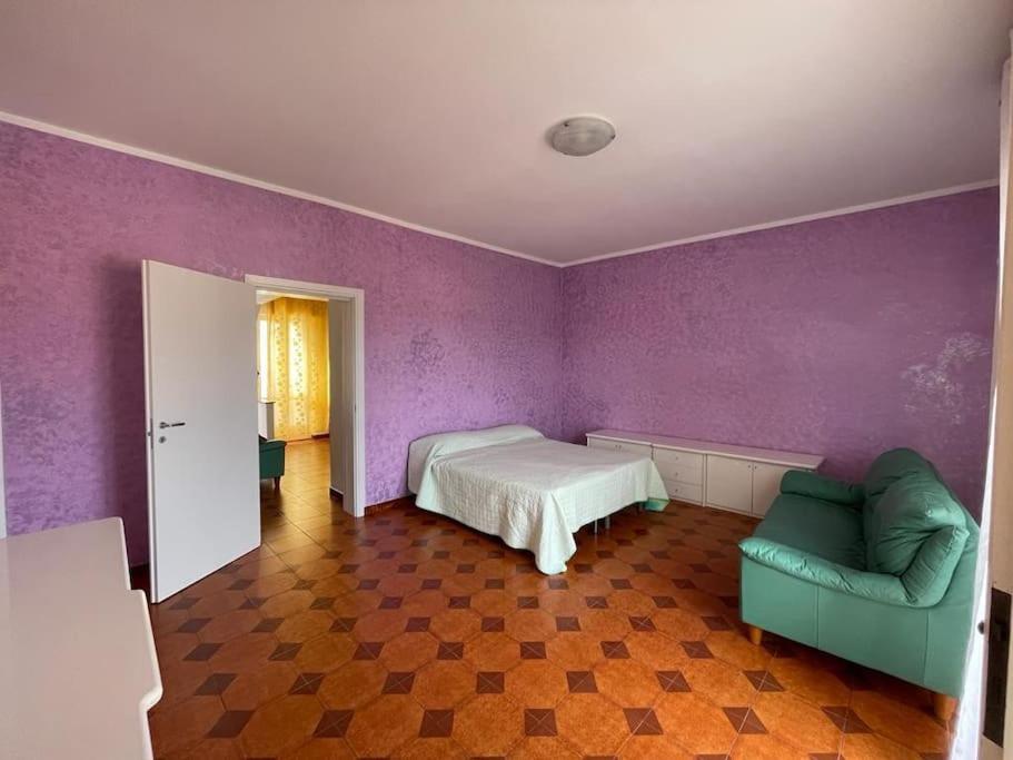 ein Schlafzimmer mit lila Wänden und einem Bett und einem Sofa in der Unterkunft Casa Elena in Gonnesa