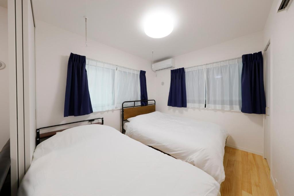 two beds in a small room with blue curtains at Setagaya House in Tokyo