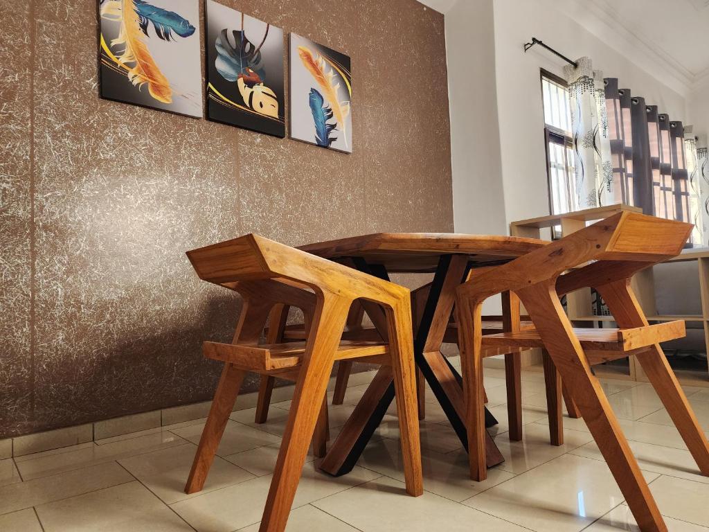 una mesa de madera y sillas en una habitación en KADIDJA APARTMENTS & SUITES Akodessewa, en Lomé