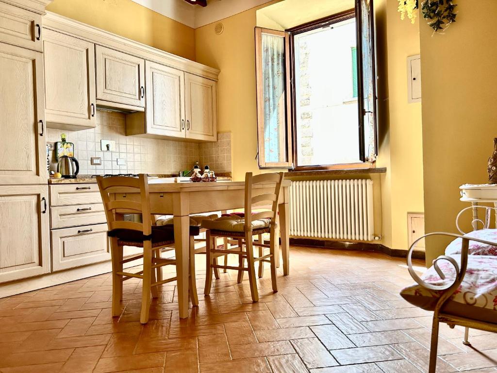 una cucina con tavolo, sedie e finestra di A Casa di Marzia a Rapolano Terme