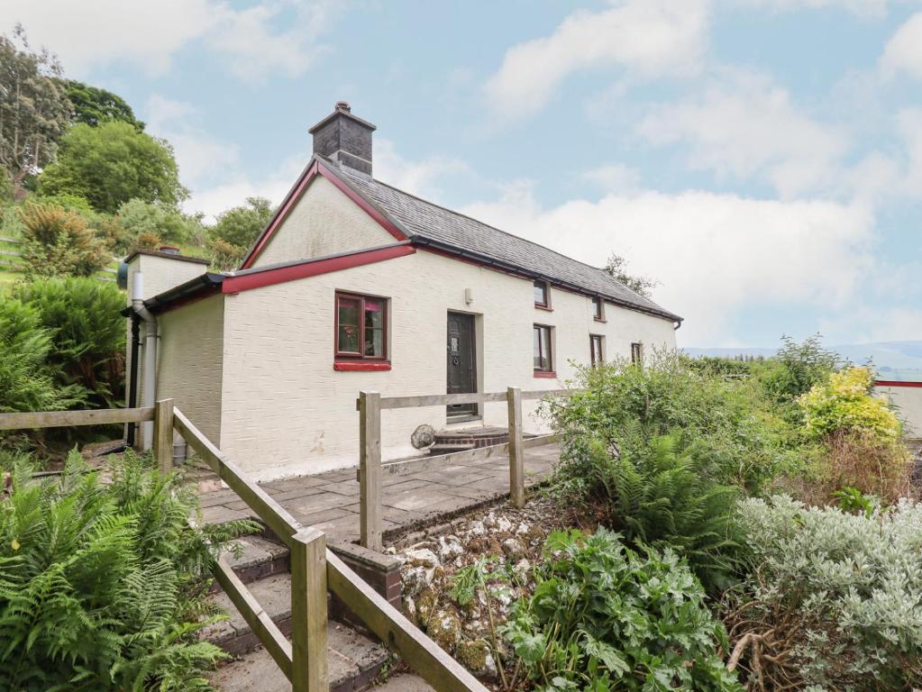 uma pequena casa branca com uma rampa de madeira que a conduz em Cefn em Machynlleth