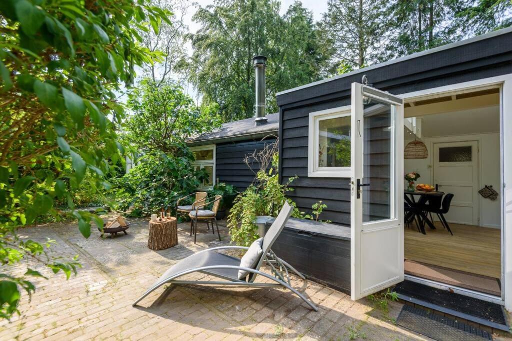 ein schwarzes winziges Haus mit einer Terrasse und einem Stuhl in der Unterkunft Rustgevend Paradijs aan het Bos in Putten