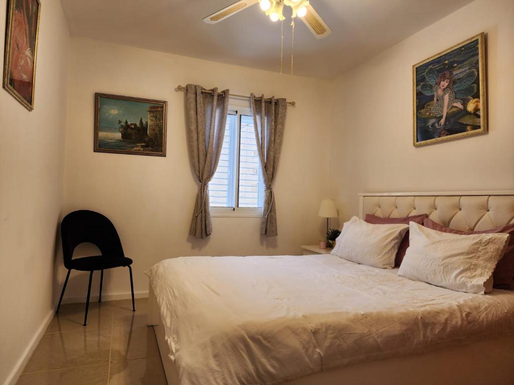 een slaapkamer met een bed, een stoel en een raam bij Краткосрочная посуточная аренда Бат-Ям! in Bat Yam