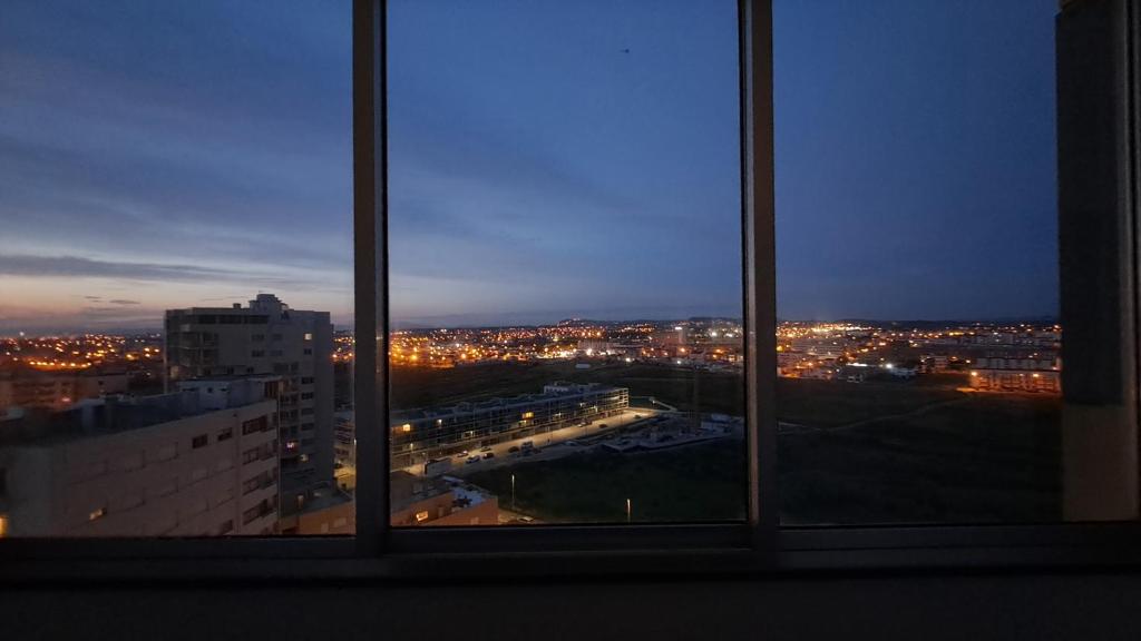 a view of a city from a window at night at SUNSET APTO in Póvoa de Varzim