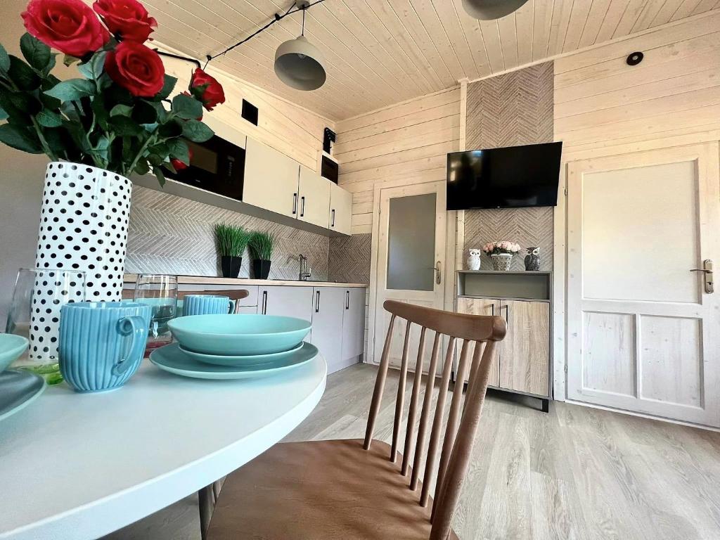 eine Küche mit einem Tisch und einer Vase aus roten Rosen in der Unterkunft Domki - Sosnowy Las in Pobierowo