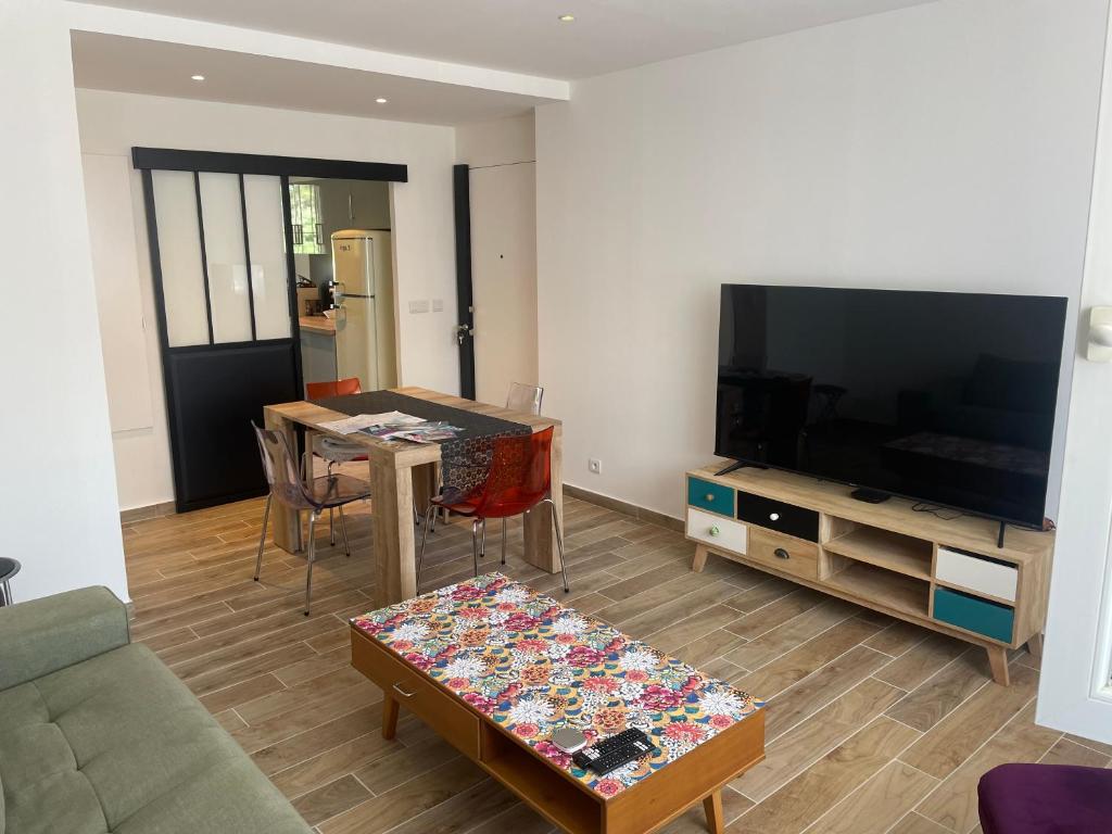 a living room with a table and a large screen tv at La Serane Appartement T3 in Marseille