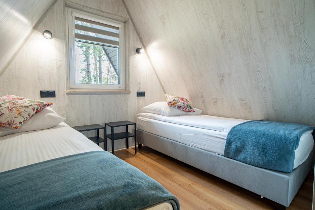 een kleine slaapkamer met 2 bedden en een raam bij Ośrodek Wypoczynkowy Kalwa in Pasym
