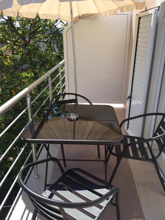 un tavolo e una sedia su un balcone con ombrellone di Apartmani Padrov a Igalo
