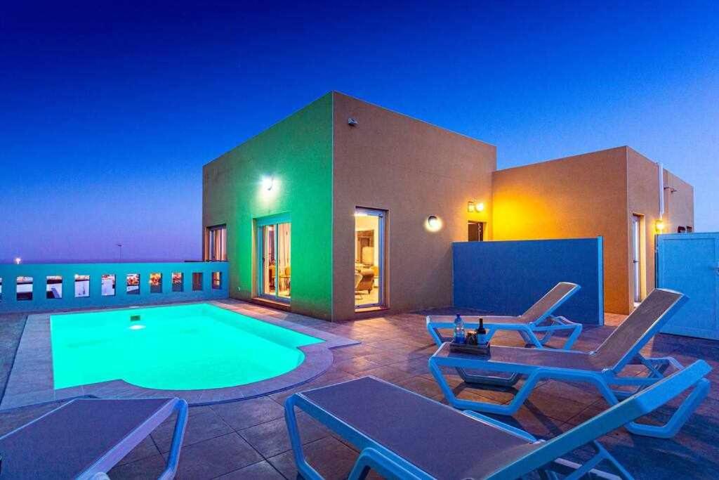 a house with a swimming pool and some chairs at Villa Horizon in Caleta De Fuste