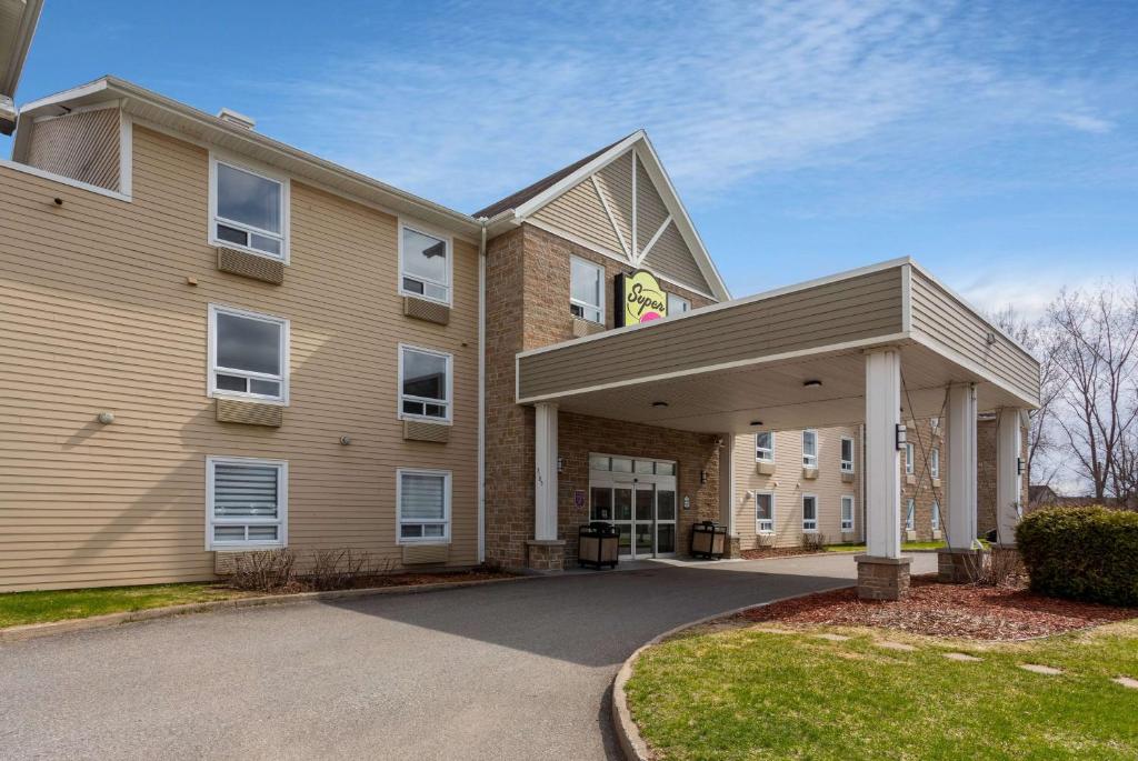 a large building with a driveway in front of it at Super 8 by Wyndham Trois-Rivieres in Trois-Rivières