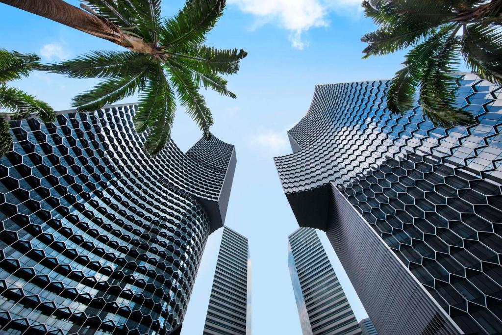 two tall buildings with palm trees in the foreground at Andaz Singapore A Concept by Hyatt in Singapore
