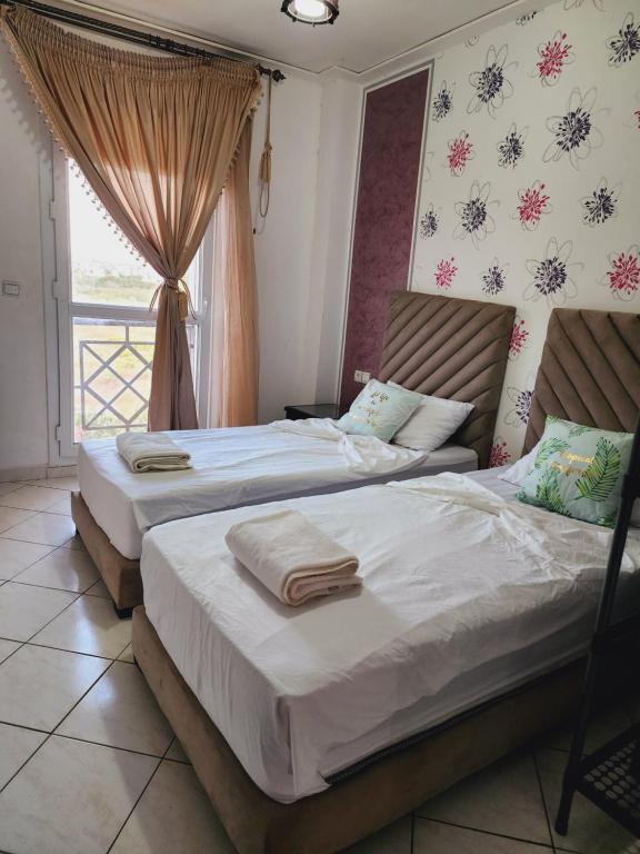 two twin beds in a bedroom with a window at FamilyConfort Saidia in Saïdia