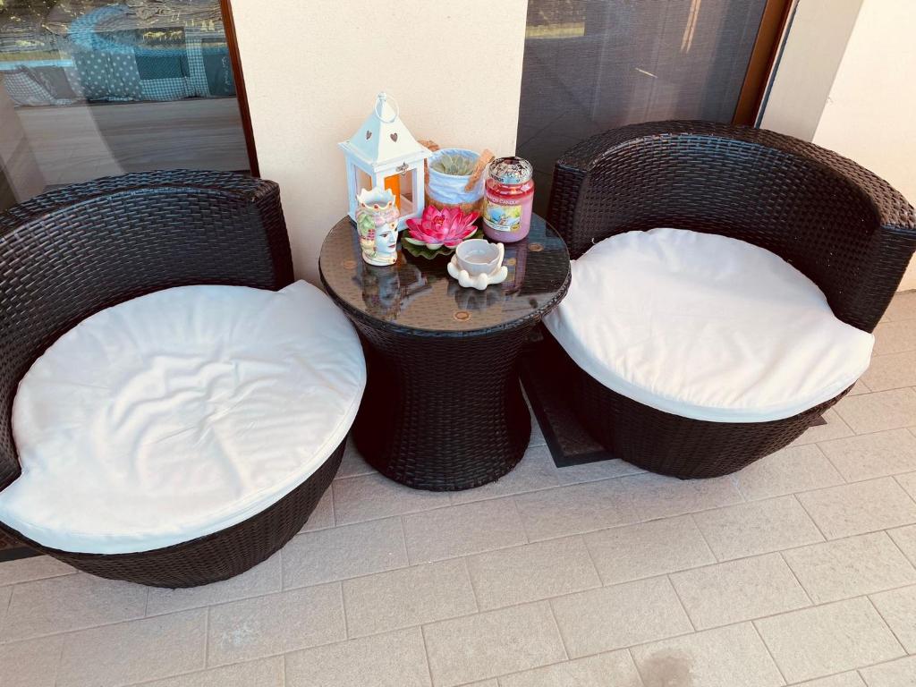 2 sillas de mimbre con cojines blancos y una mesa en B&B VALE, en Viarolo