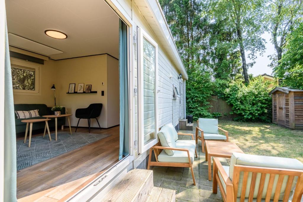 - une terrasse couverte avec des chaises, une table et un canapé dans l'établissement Chalet met eigen tuin aan de Veluwse bosrand, à Putten