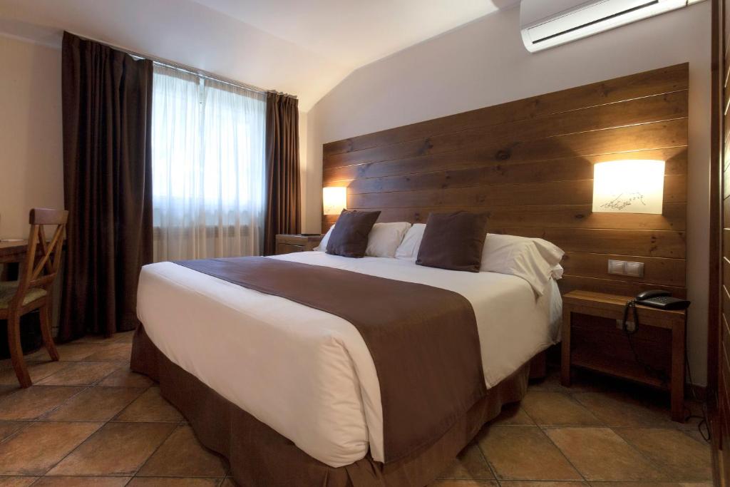 1 dormitorio con 1 cama grande y pared de madera en Hotel Màgic La Massana, en La Massana