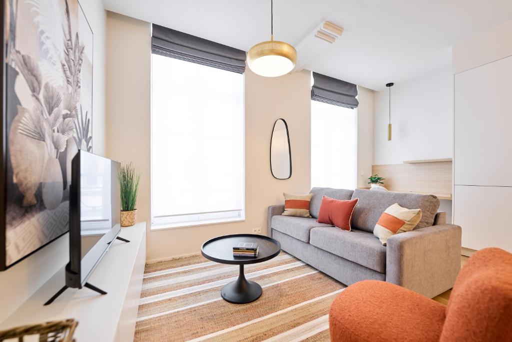 ein Wohnzimmer mit einem Sofa und einem TV in der Unterkunft Place du Grand Sablon in Brüssel