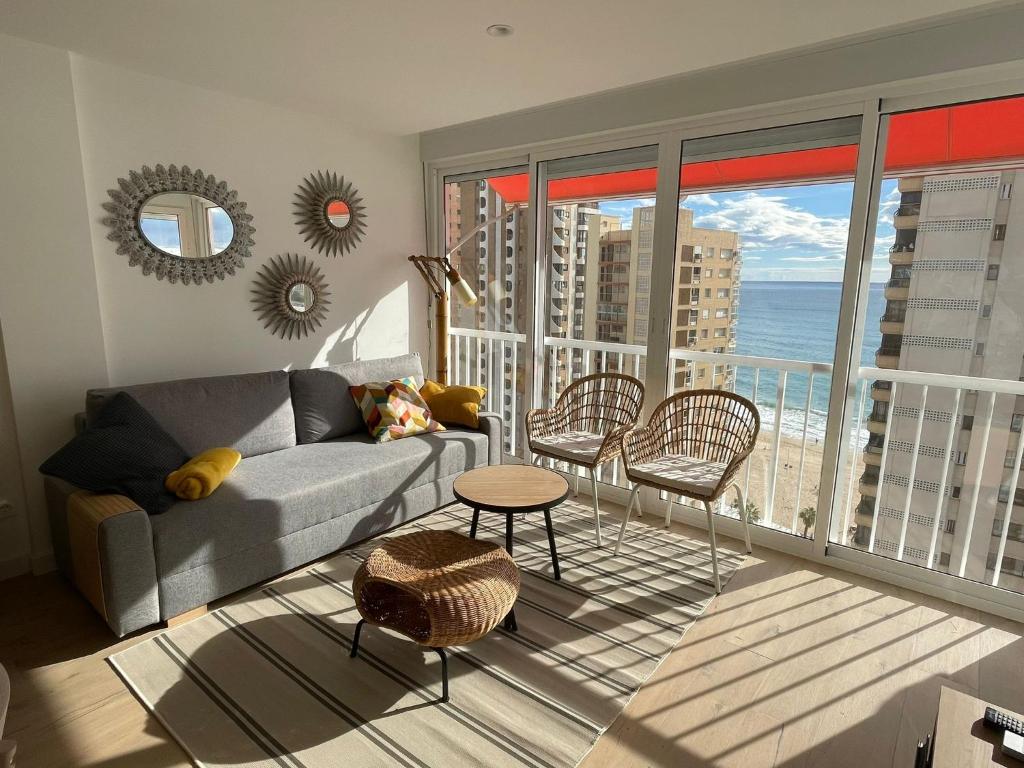 een woonkamer met een bank en uitzicht op de oceaan bij Apartamento turístico Playmon Bacana Planta 14 in Benidorm