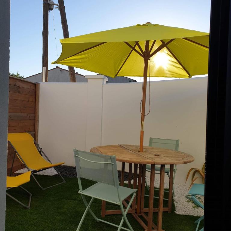 une table et des chaises avec un parapluie jaune dans l'établissement Guest House entre ville et océan, à La Rochelle