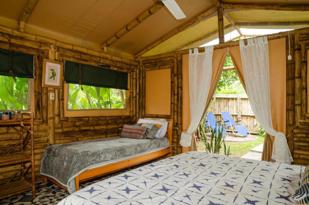 1 dormitorio con 2 camas en una habitación con ventana en Aguas Claras Bamboo Ecolodge, en Guaduas