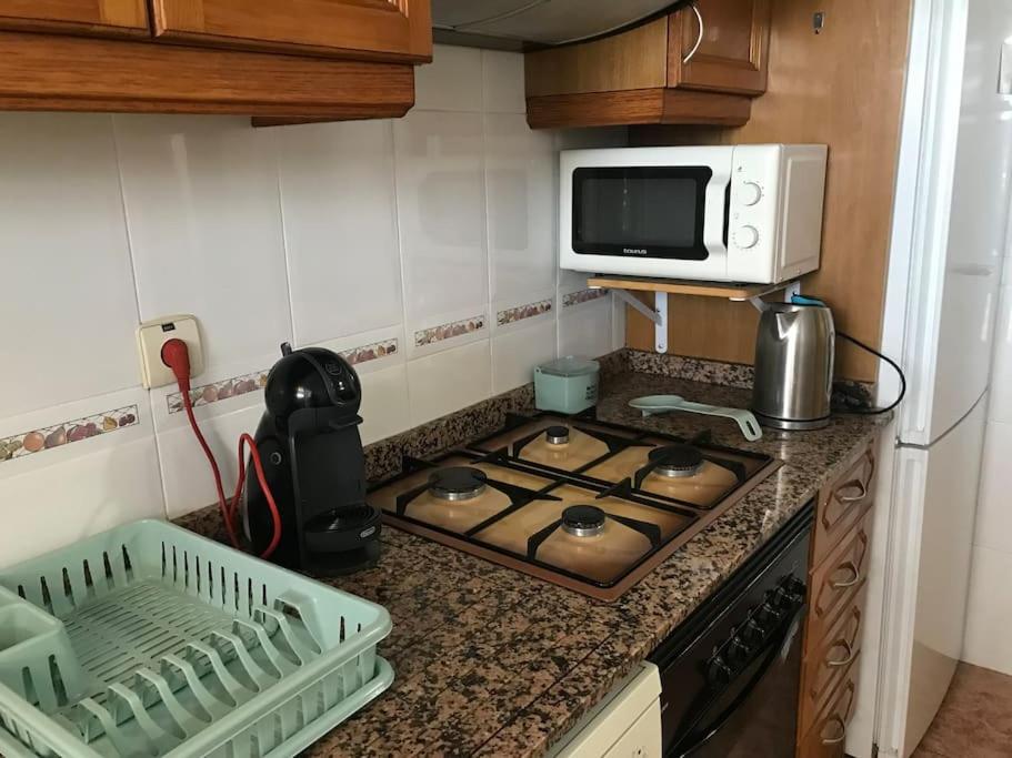 a kitchen counter with a stove and a microwave at Apartamento cómodo y espacioso con parking in Valencia