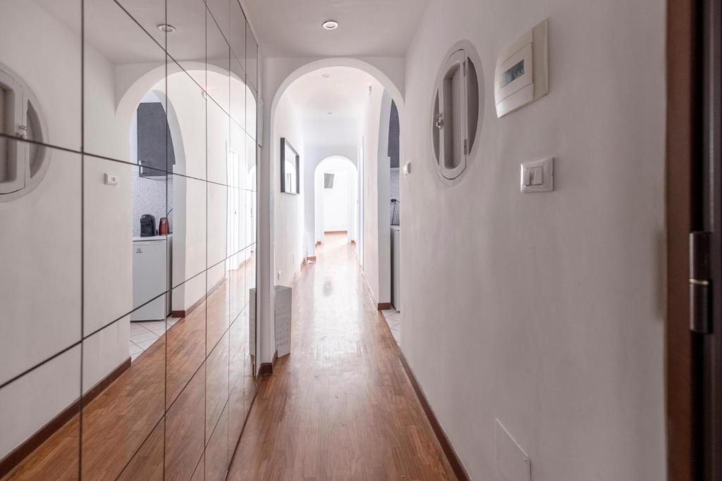 um corredor com paredes brancas, pisos em madeira e um espelho em Art House Centro Storico Luxury Apartment em Roma
