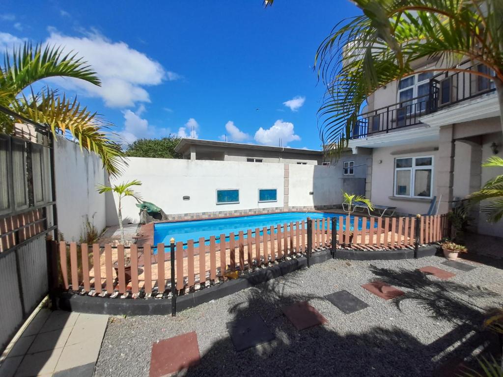 a swimming pool in front of a house with a fence at Fina Villa Apartments - Mont choisy in Mont Choisy