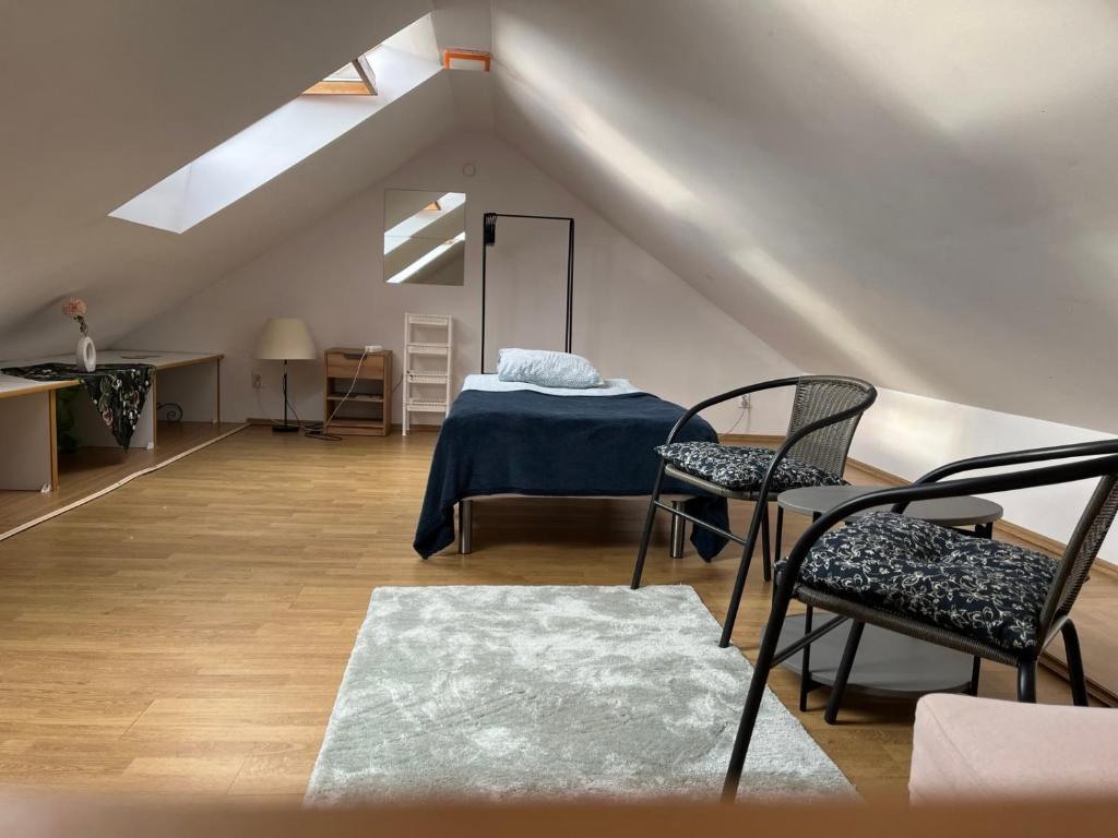 a attic room with a bed and two chairs at Dandelion Noclegi in Warsaw