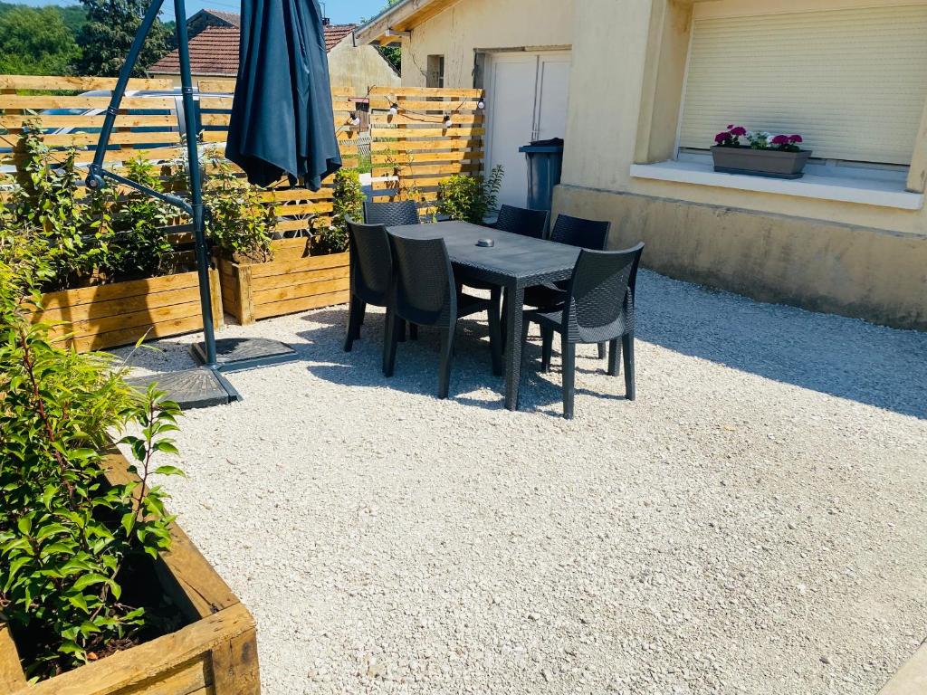 a table with chairs and an umbrella on a patio at Le Biclou- 3 chambres in Bazincourt-sur-Saulx