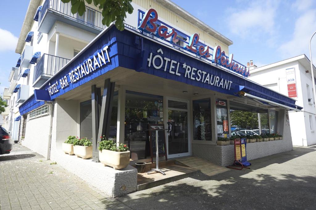 a hotel restaurant with a blue sign on a building at Hotel les Pecheurs in Lorient