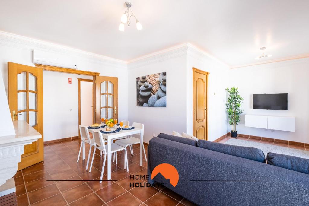 #020 Olhos d'Água with Shared Pool, Heated Floor في ألبوفيرا: غرفة معيشة مع أريكة زرقاء وطاولة