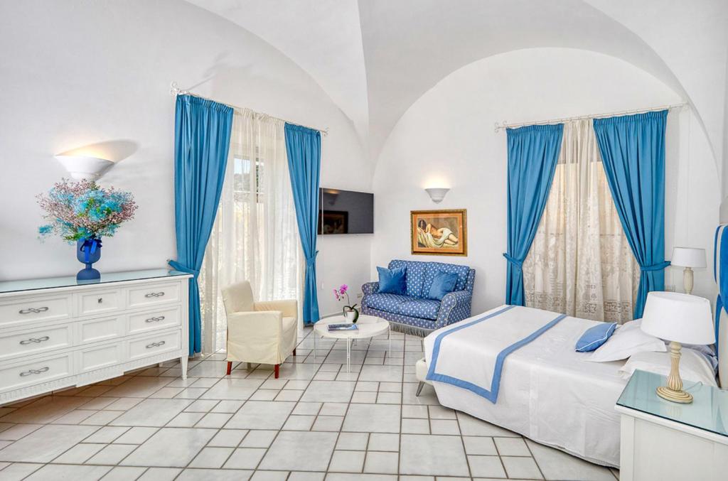 Le Botteghe 59 Capri في كابري: غرفة نوم مع ستائر زرقاء وسرير وكرسي