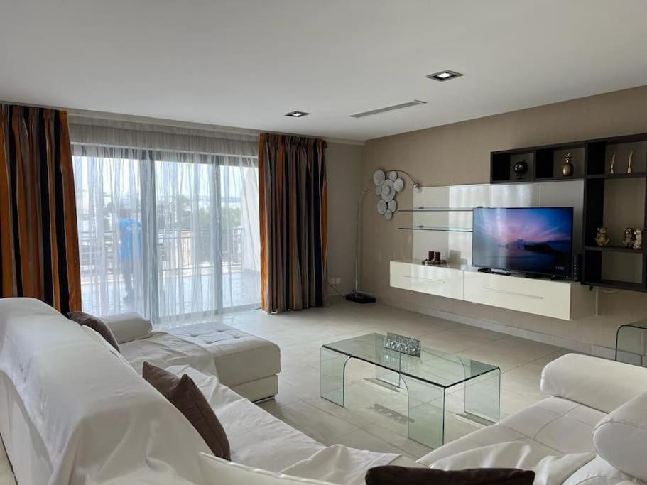 uma sala de estar com um sofá branco e uma televisão em Luxury 3-Bedroom Apartment in St Julians em St. Julian's